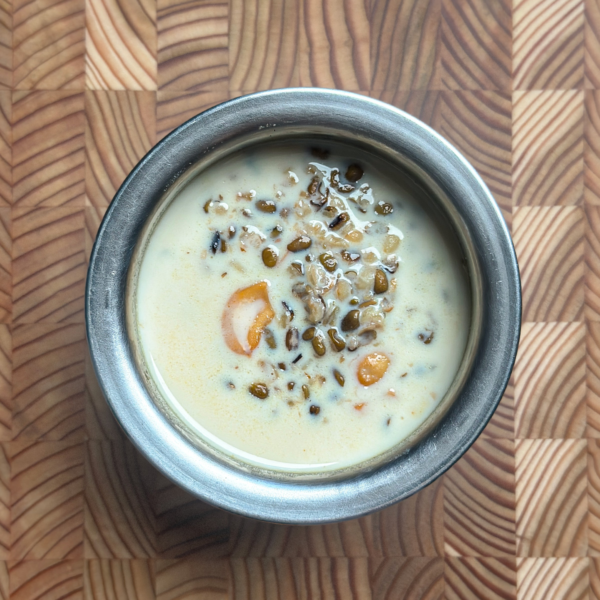 Traditional moong dal payasam served in ceramic bowl on wooden table