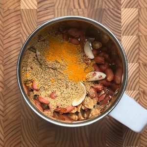 Roasted peanuts, garlic, and colorful spice powders in a mixer grinder