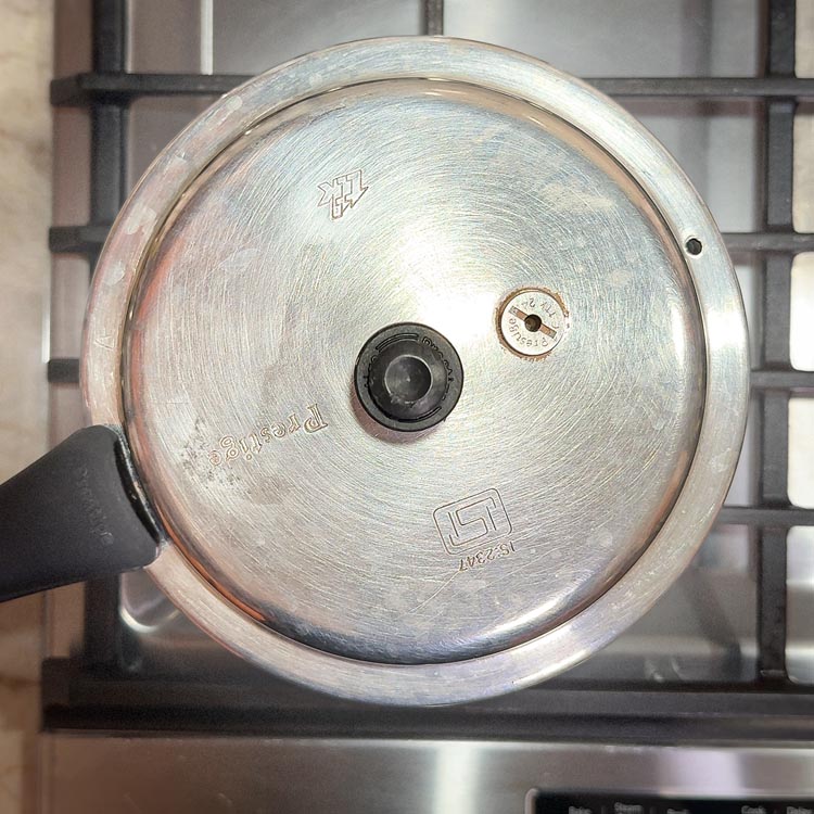 Traditional pressure cooker with whistle on gas stove burner