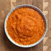 Vibrant orange-red Erra Karam with coarse texture served in traditional blue and white ceramic bowl on wooden surface