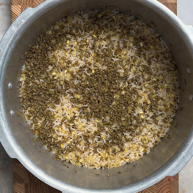 Fully cooked rice and moong dal mixture with fluffy texture visible in pressure cooker