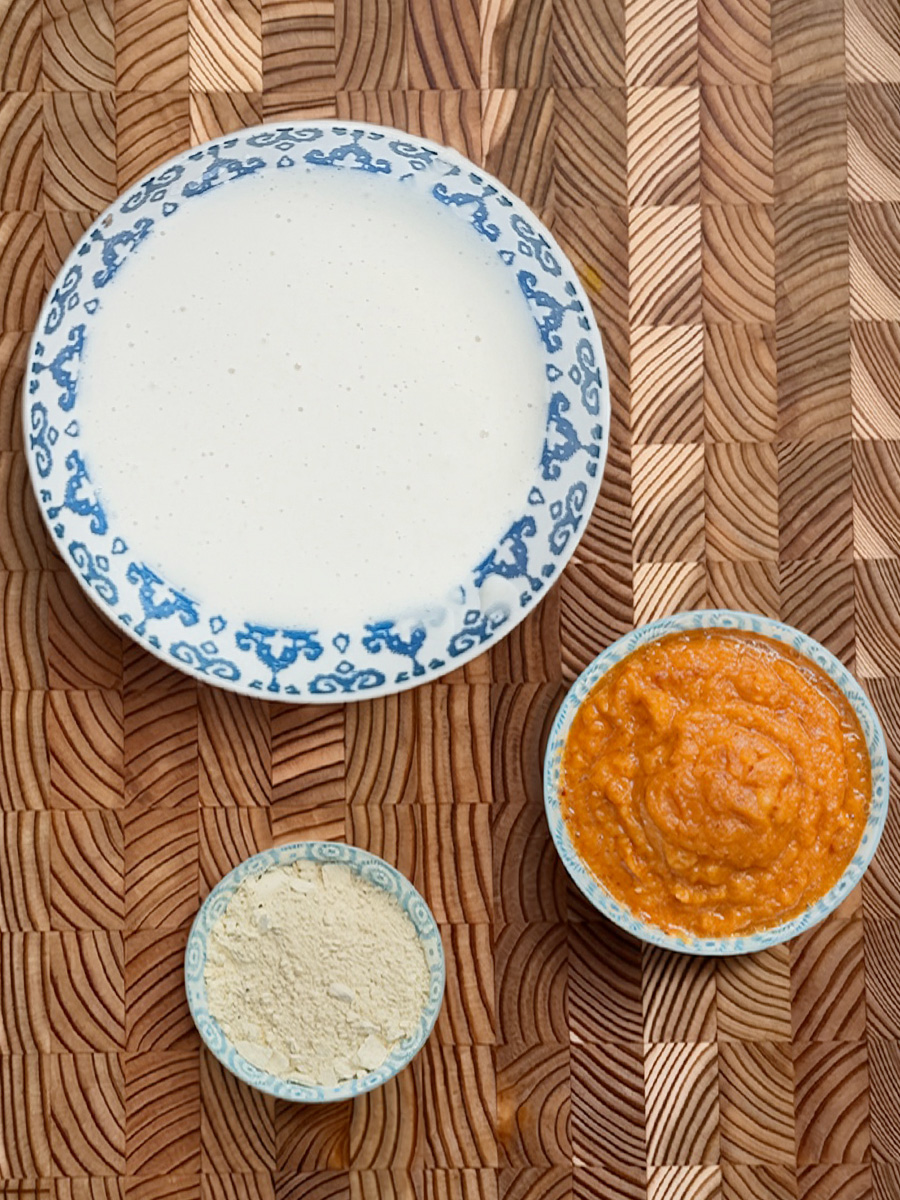 All ingredients for Erra Karam Dosa recipe - white plate with bowls of red chutney and beige lentil powder