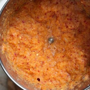 Raw onion chunks, whole dried red chilies, tamarind, and white salt combined in mixi ready for grinding