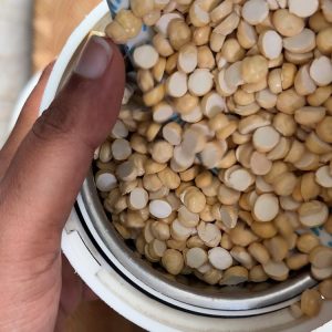 Fine pale yellow chana dal powder in spice grinder jar after grinding process