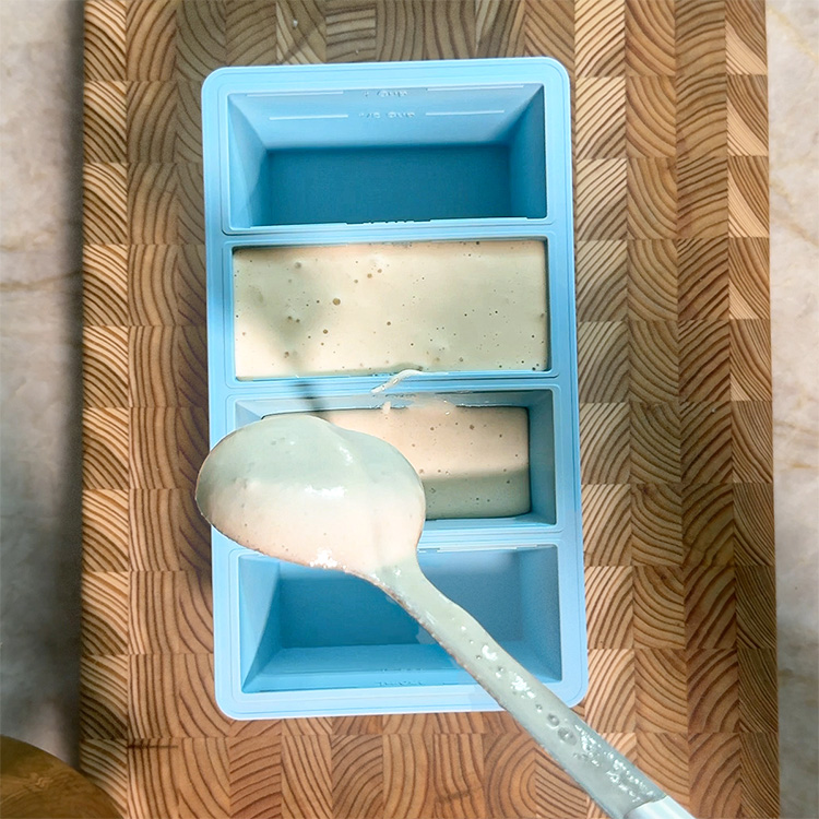 Fermented dosa batter frozen in blue silicone ice cube tray with ladle, showing portion control storage method