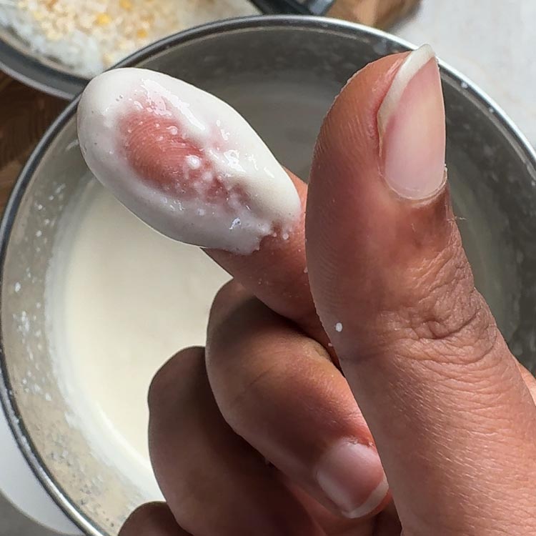 Perfect smooth dosa batter consistency on spoon showing proper grinding texture