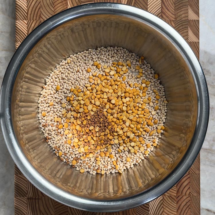 Dry ingredients for dosa batter: Sona Masoori rice, urad dal, chana dal and fenugreek seeds in steel bowl