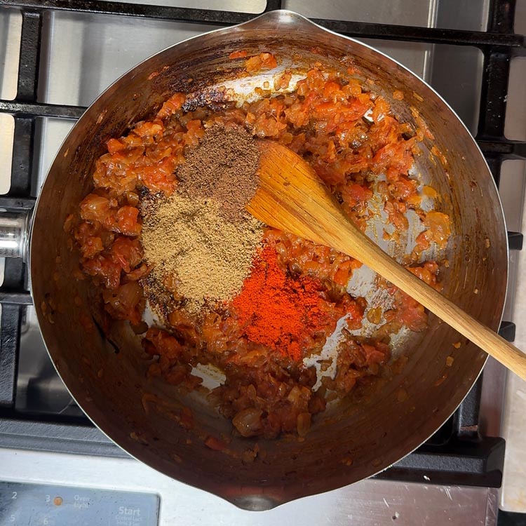 Turmeric, coriander, and chili powder cooking in thick tomato onion base until fragrant