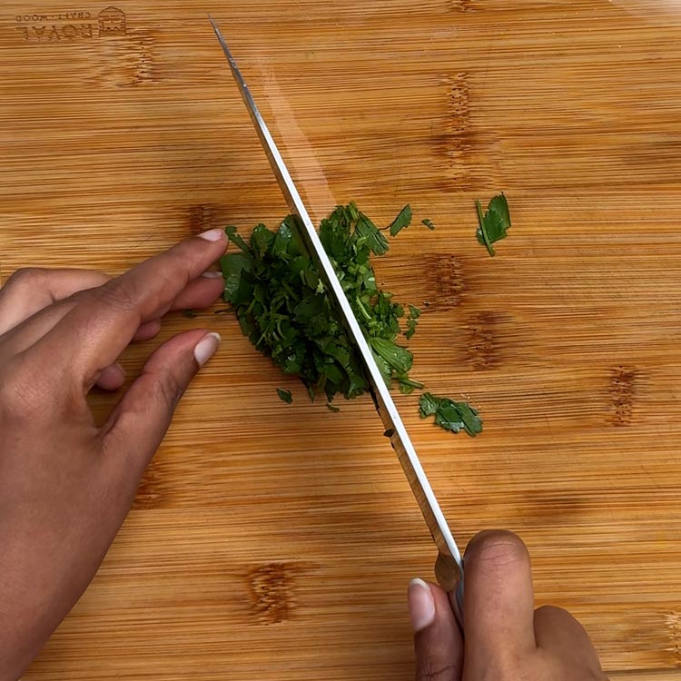 Uniformly diced white onions on bamboo cutting board with sharp knife
