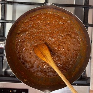 Turmeric, coriander, and chili powder cooking in thick tomato onion base until fragrant