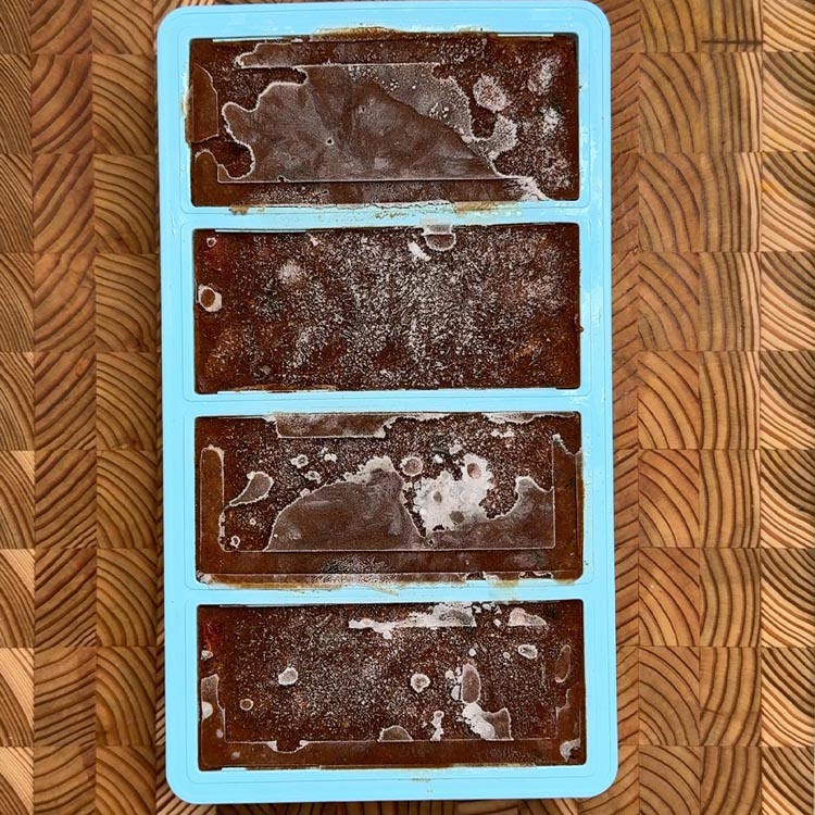 Four blue meal prep containers with curry frozen crystals showing freezer storage preparation