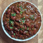 Finished high protein rajma curry in white bowl garnished with fresh coriander leaves