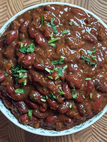 Finished high protein rajma curry in white bowl garnished with fresh coriander leaves