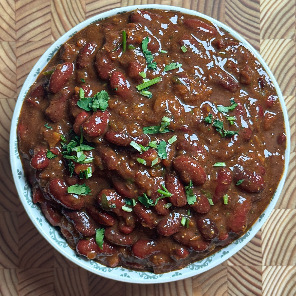 Finished high protein rajma curry in white bowl garnished with fresh coriander leaves