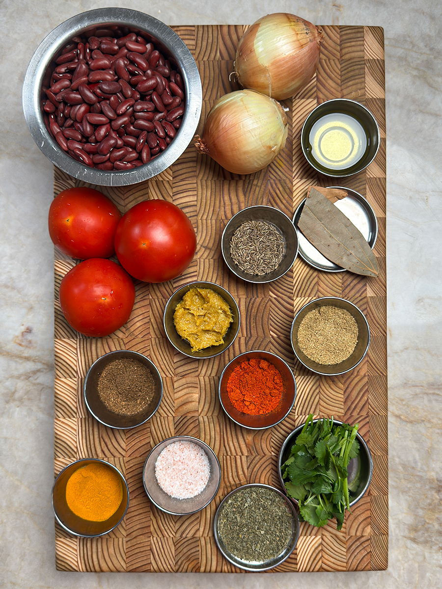 High protein rajma curry ingredients including red kidney beans, tomatoes, onions, and spices arranged on wooden board