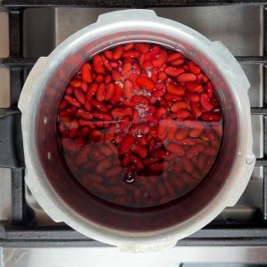Red kidney beans in pressure cooker about to be cooked with water and salt