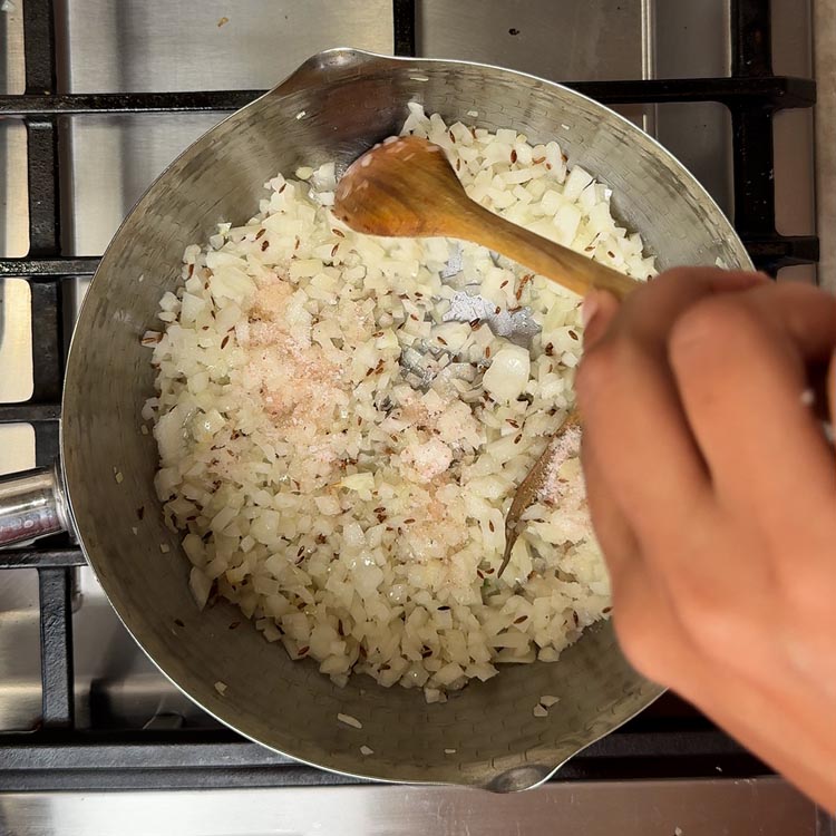 Chopped onions cooking with salt in pan until golden brown and translucent