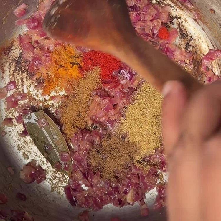 Ground spices creating a fragrant, aromatic paste in the oil before adding liquids, showing the spice bloom technique