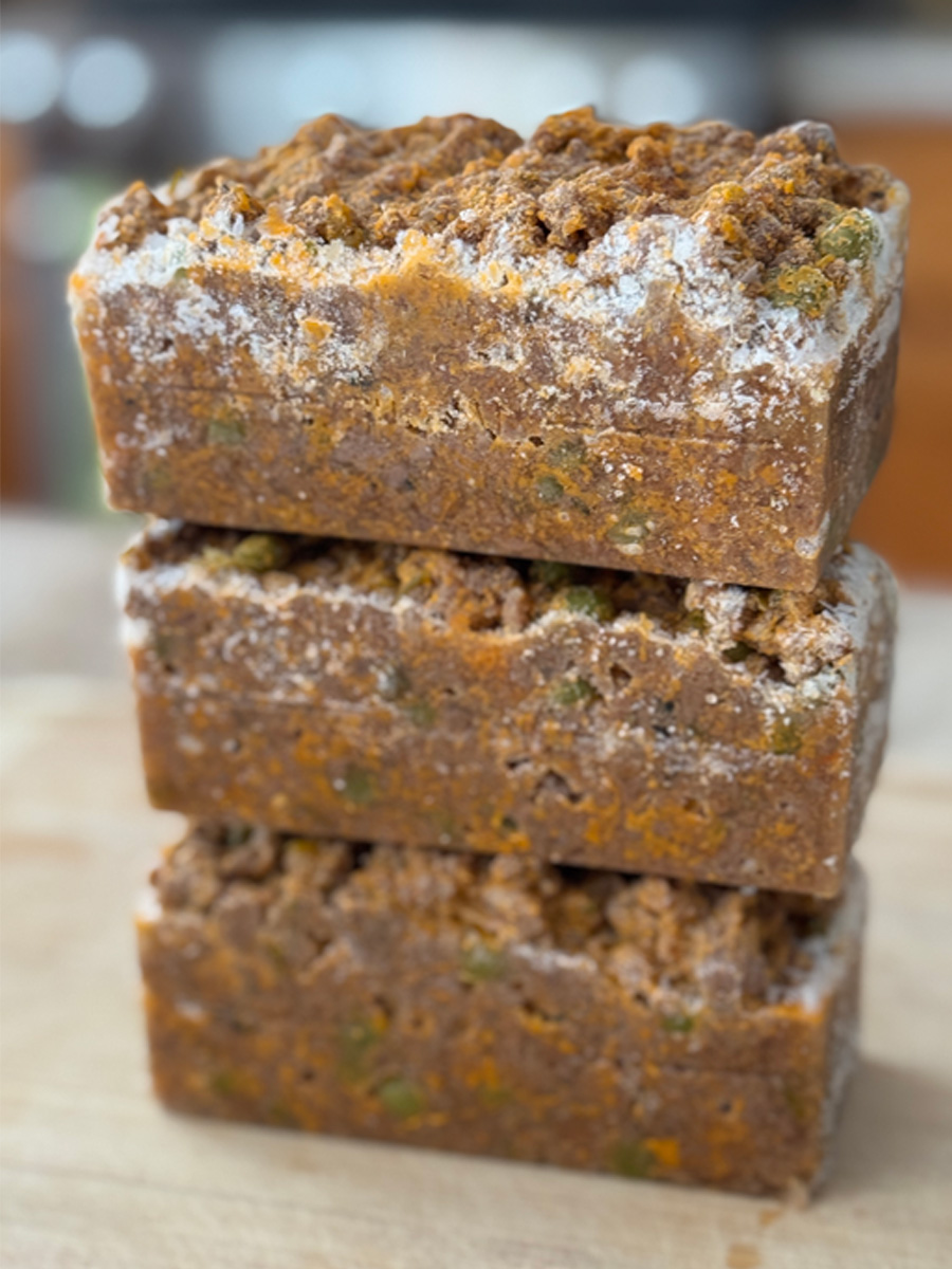 Three frozen lamb keema blocks stacked showing freezer meal prep with visible peas