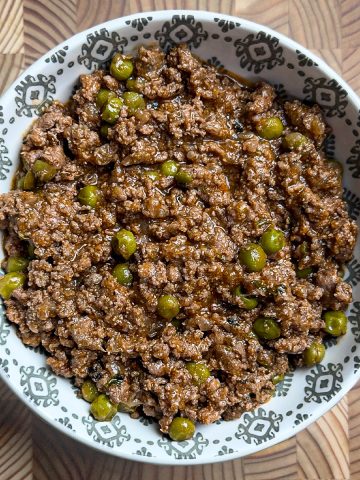 Lamb keema matar served in white decorative bowl showing tender meat and green peas