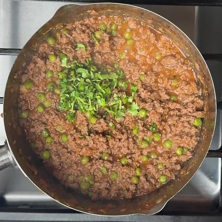 Finished lamb keema matar garnished with fresh chopped coriander, green peas visible throughout
