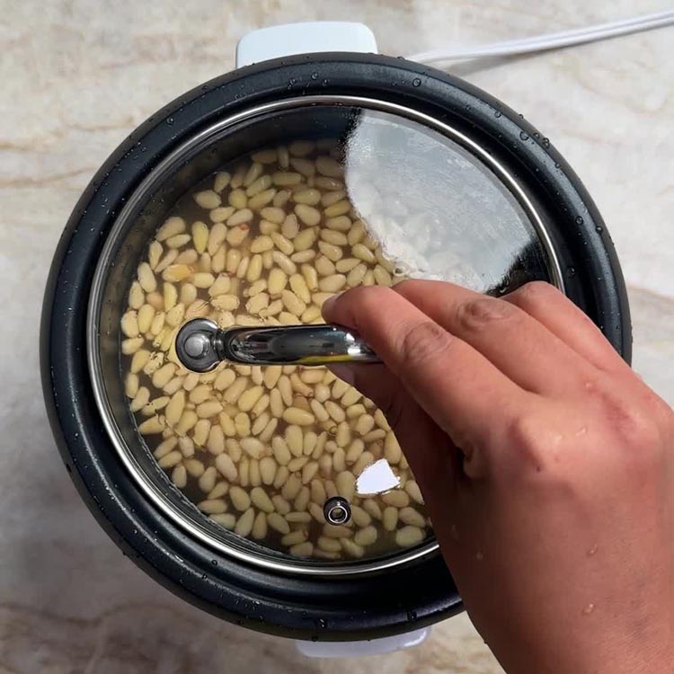 Rice cooker interior showing fully cooked rice mixed with toasted pine nuts