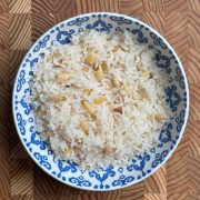 Pine nut white rice served in blue and white porcelain bowl, fluffy texture with golden nuts distributed throughout