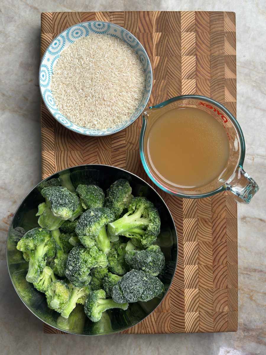 Recipe ingredients: white rice in bowl, golden chicken bone broth in measuring cup, and frozen broccoli florets