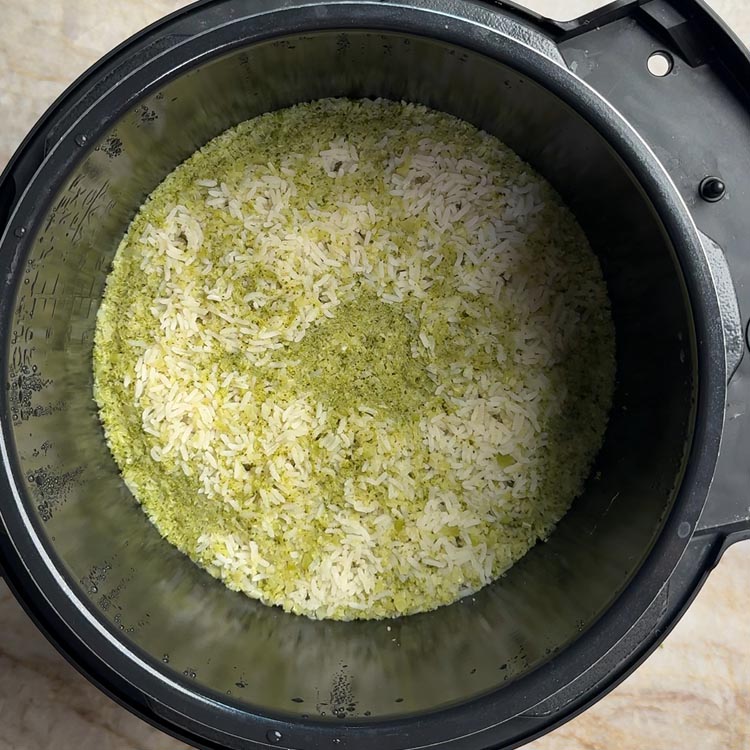 Fluffy broccoli rice with bone broth freshly cooked in pressure cooker showing white and green speckled texture