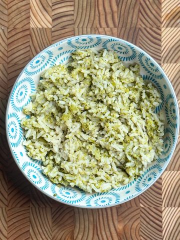 Easy broccoli rice with bone broth served in a blue and white patterned bowl on wooden cutting board