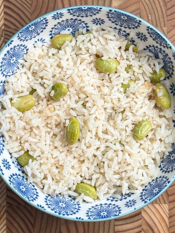 High-protein edamame rice with chicken broth served in a blue and white patterned bowl, fluffy rice mixed with vibrant green edamame
