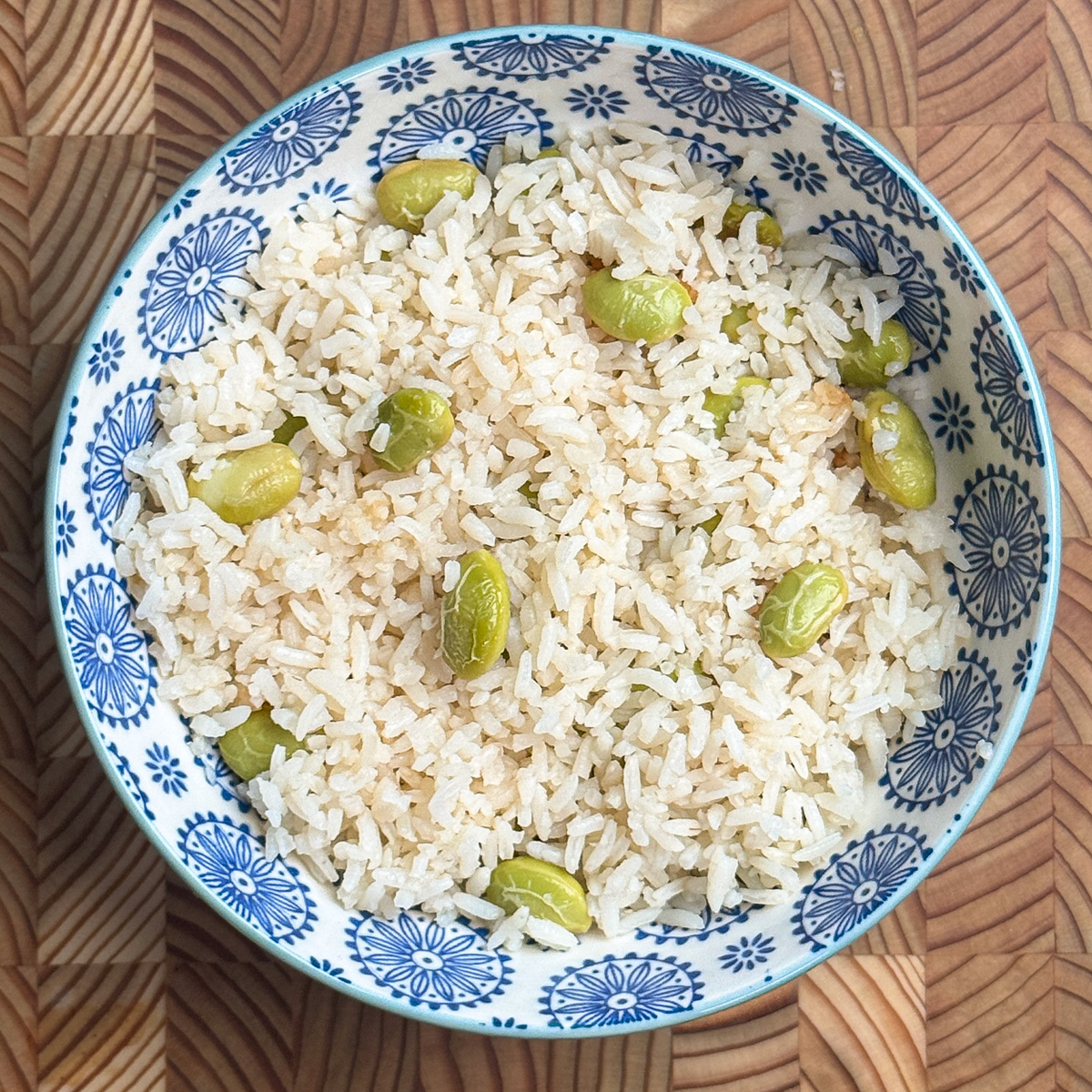 High-protein edamame rice with chicken broth served in a blue and white patterned bowl, fluffy rice mixed with vibrant green edamame