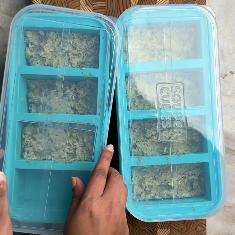 Two teal Souper Cubes trays filled with portioned rice, lids placed on top ready for freezing