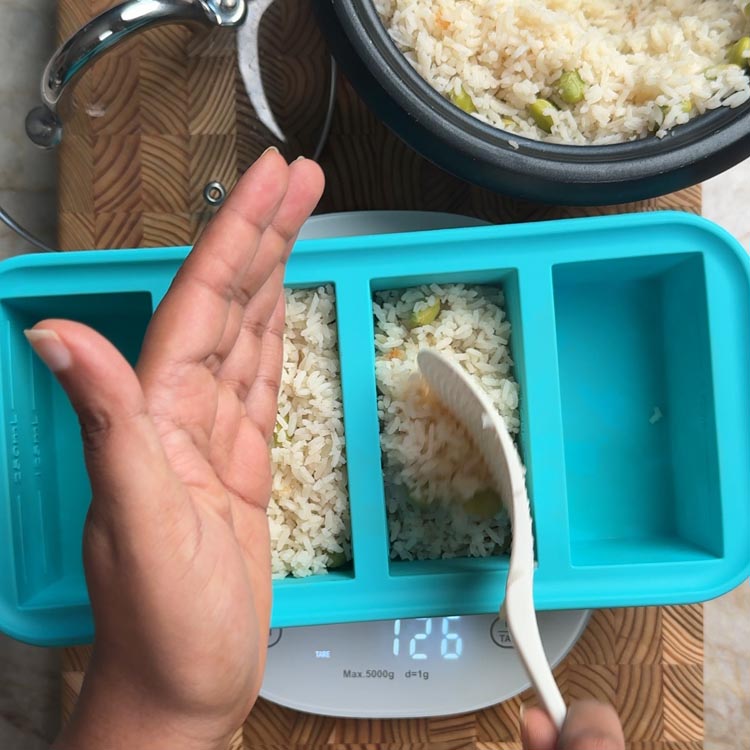 Kitchen scale showing 126g portion being lifted from turquoise meal prep container