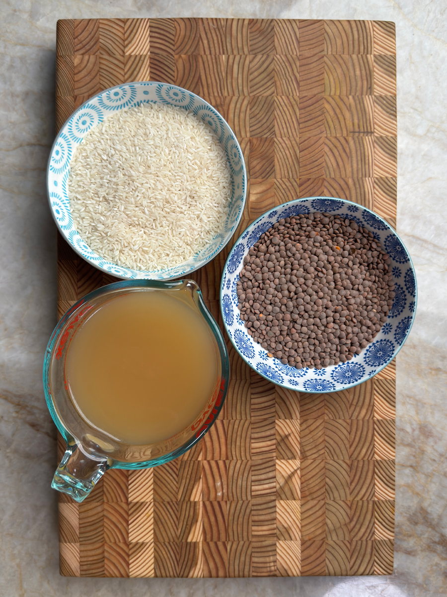 High protein masoor dal rice ingredients: white rice in blue bowl, brown whole masoor dal in patterned bowl, and golden chicken broth in measuring cup