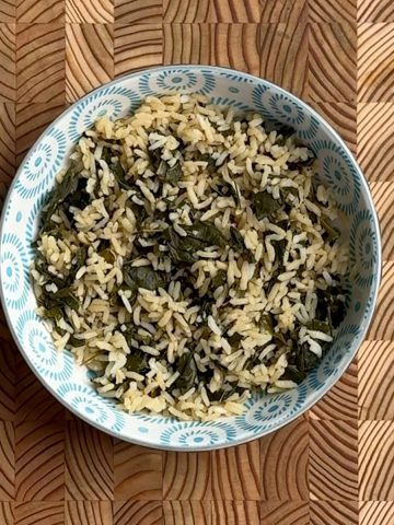 Cooked moringa leaves protein boosted rice with green leaves distributed throughout white rice grains