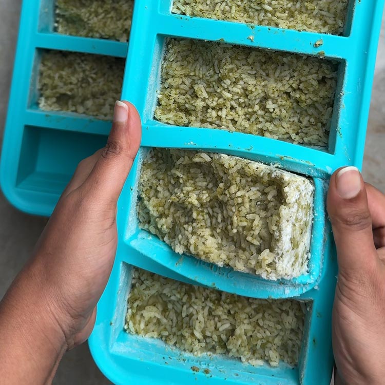 Hands flexing silicone Souper Cubes tray to release frozen rice portions