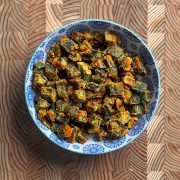 Crispy baked besan okra with golden orange chickpea flour coating in blue and white decorative bowl