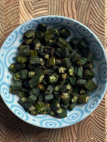 Crispy baked frozen okra in a blue and white patterned ceramic bowl on a wooden surface