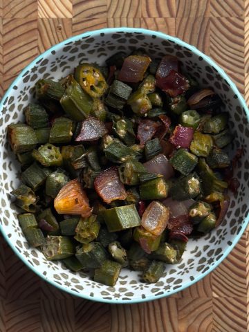 Crispy baked okra with roasted onions in white bowl, golden brown and ready to serve