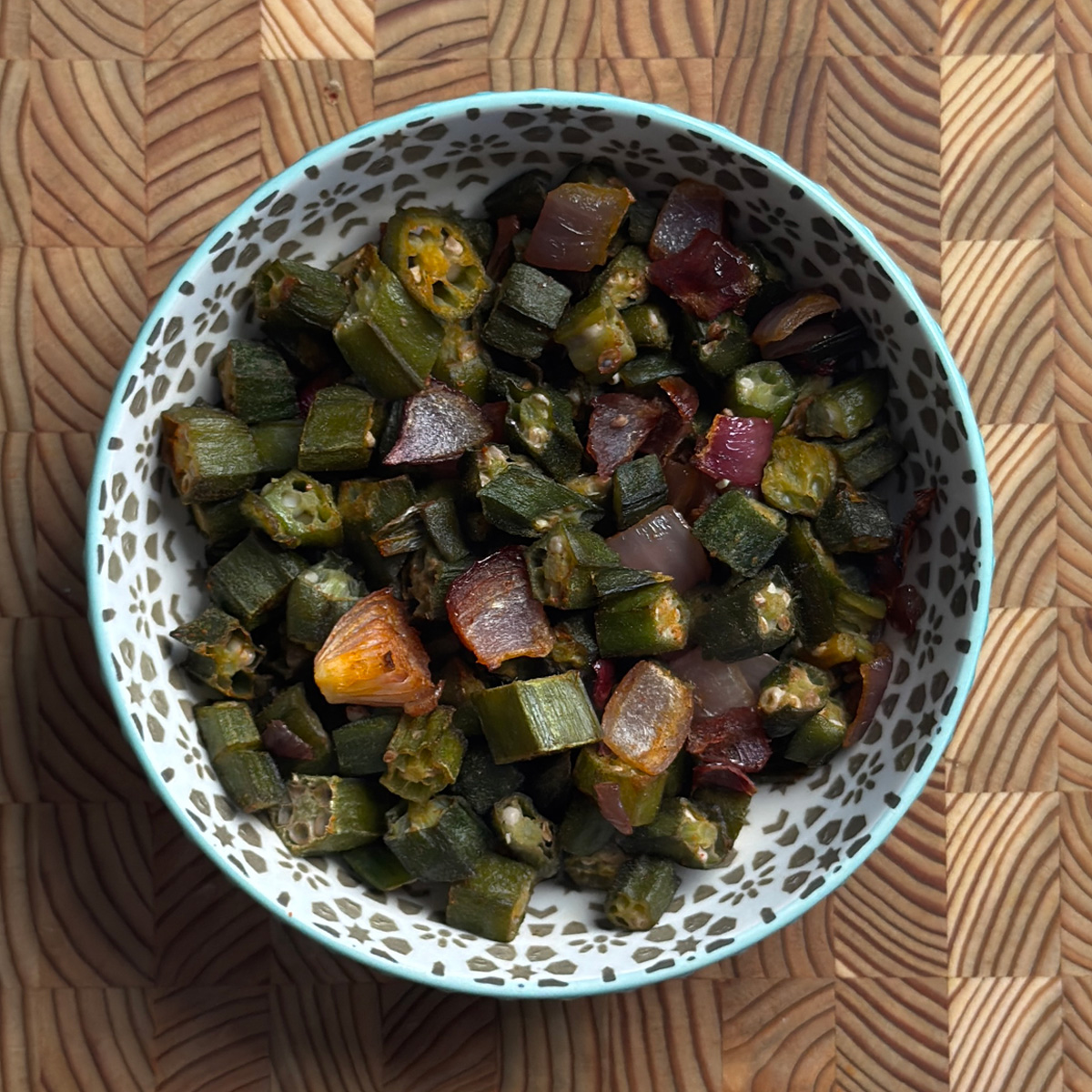 Crispy baked okra with roasted onions in white bowl, golden brown and ready to serve