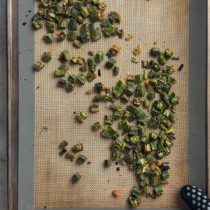 Crispy baked okra with garlic podi on sheet pan with golden brown toasted coconut coating