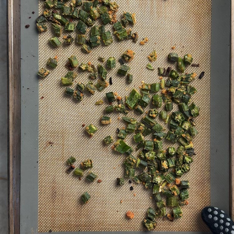 Crispy baked okra with garlic podi on sheet pan with golden brown toasted coconut coating