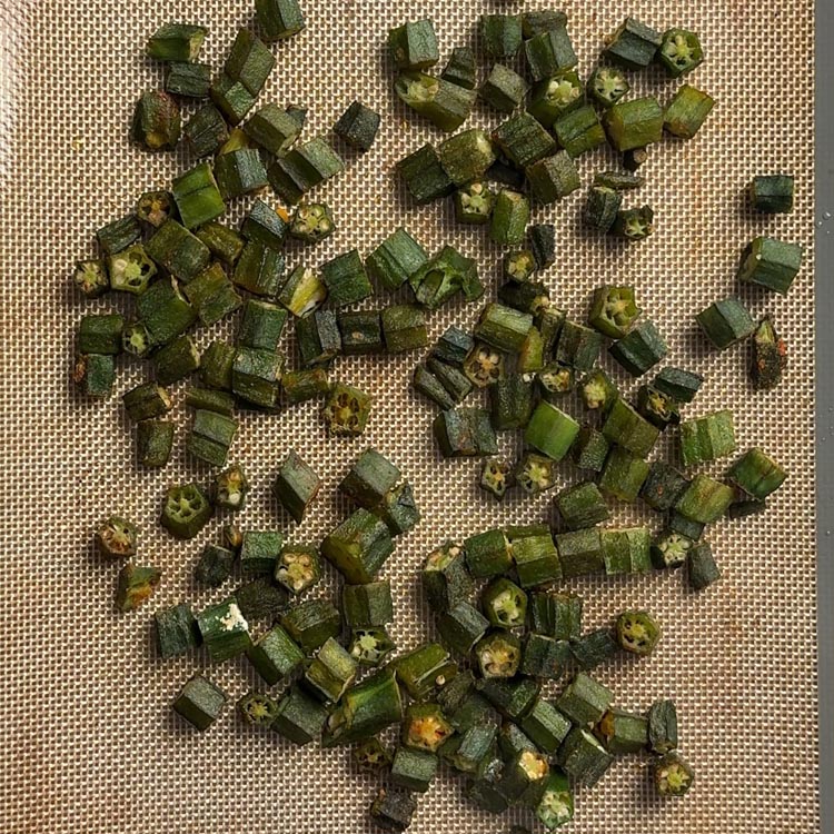Fully baked okra after 30 minutes showing deep golden brown crispy edges on a baking mat