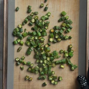 Okra pieces after 15 minutes of baking, showing early browning on a silicone mat