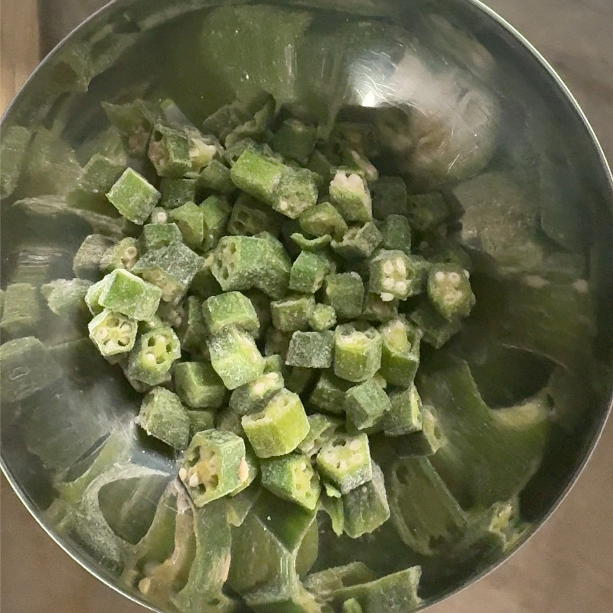 Pre-cut frozen okra ready to cook in a metal bowl