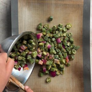 Okra and onion pieces spread in single layer on sheet pan before baking