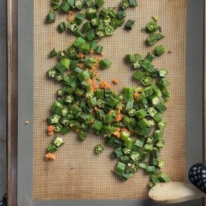 Okra pieces coated with orange garlic podi powder on sheet pan during baking