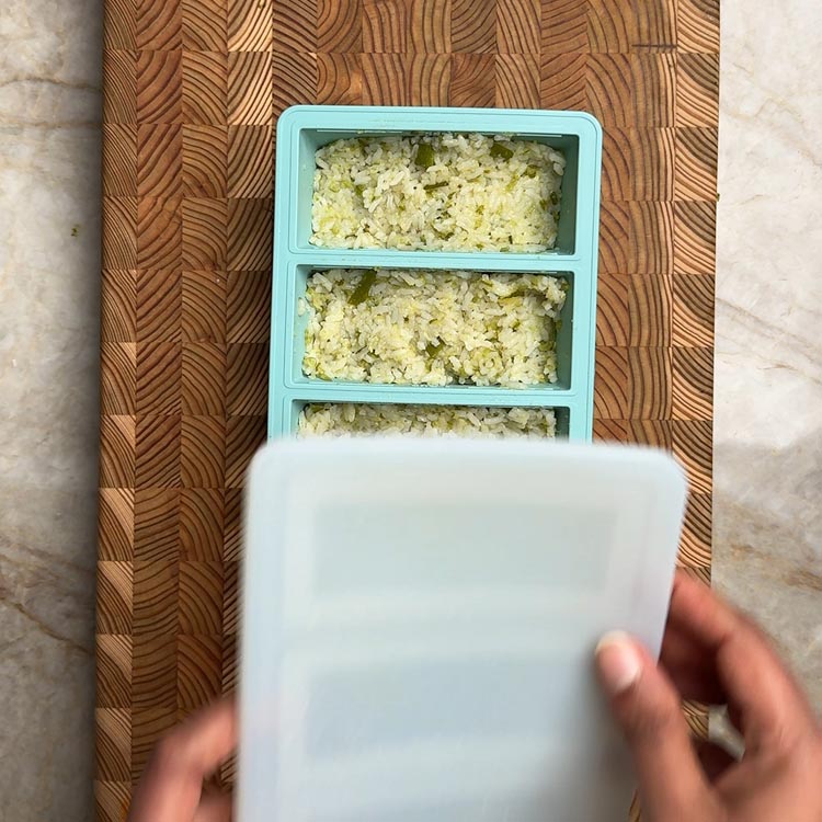 Teal tray filled with portioned rice, lids placed on top ready for freezing