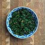 Spicy Korean spinach side dish topped with sesame seeds in a blue patterned bowl